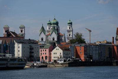 Buildings by river against sky in city