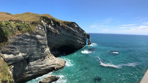 Rock formations by sea against clear blue sky