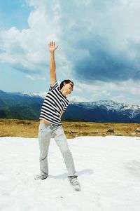 Woman standing on landscape against cloudy sky