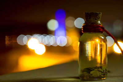 Close-up of glass bottle on table at night