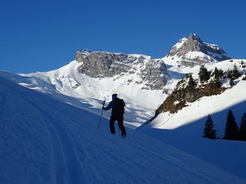 Man skiing on snowcapped mountain against sky