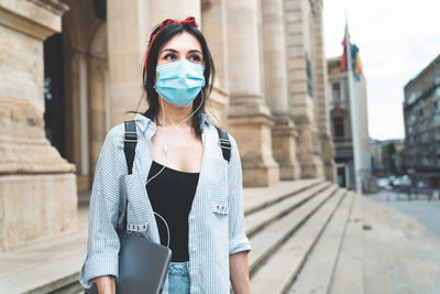 Portrait of woman standing against building in city