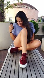 Portrait of young woman sitting on wall