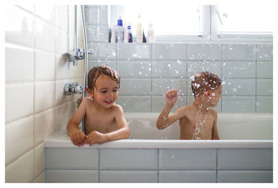 Happy siblings in bathtub at bathroom