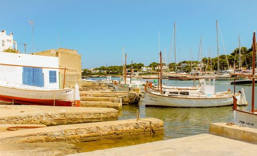 Boats moored at harbor against clear sky