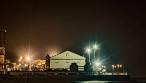 Illuminated factory against sky at night