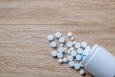 High angle view of pills spilling from bottle onto table