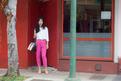 Portrait of young woman standing against building