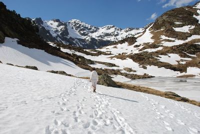 Person walking on snow covered mountain against sky