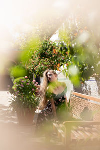 Full length portrait of young woman sitting on bench outdoors