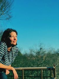 Teenage girl smiling against clear blue sky