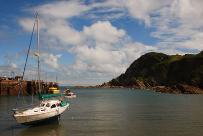 Boats in sea against cloudy sky