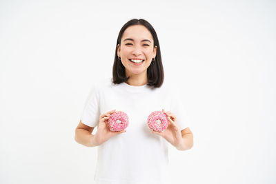 Portrait of smiling young woman gesturing against white background