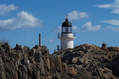 Low angle view of lighthouse by building against sky