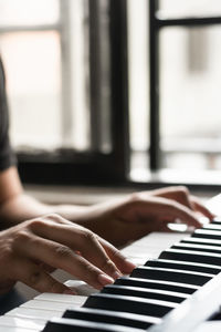 Detail shot of a boy learning to play piano at home. hands of a latin man practicing his hobby