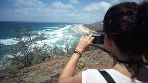 Rear view of man using mobile phone at beach