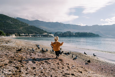 Rear view of woman walking at beach against sky