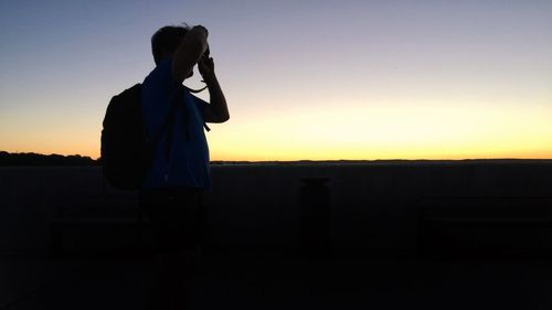 Silhouette man using smart phone against sky during sunset