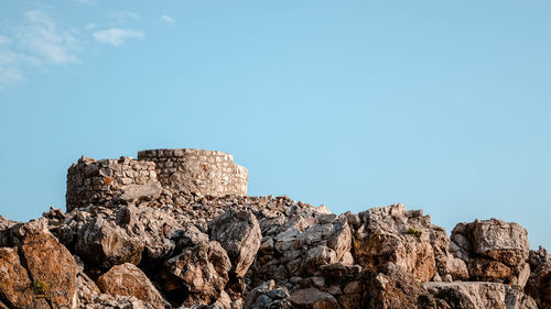 Low angle view of rocks against clear blue sky