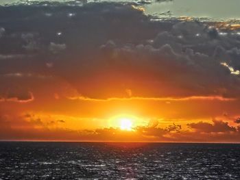 Scenic view of sea against dramatic sky during sunset