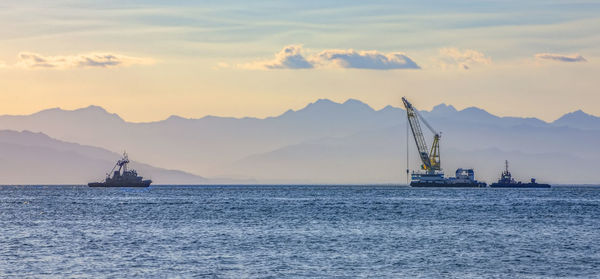 Sea ship with a crane on the background of a mountain range in the haze