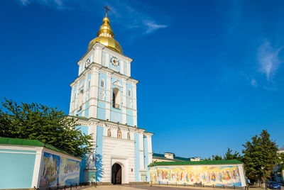 Low angle view of clock tower amidst buildings against sky