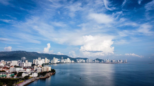 Panoramic view of bay and buildings against sky