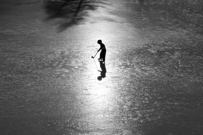 Silhouette boy playing ice hokey on ice rink