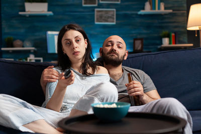 Friends looking away while sitting on sofa