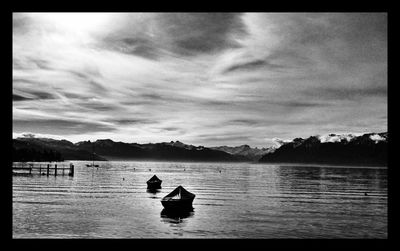 Boats in sea against cloudy sky