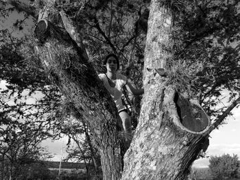 Portrait of teenage girl sitting on tree trunk