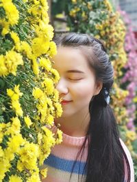 Close-up of smiling young woman smelling flowers