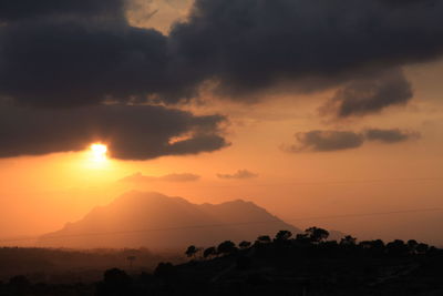 Scenic view of silhouette landscape against orange sky