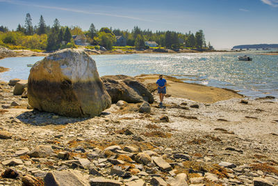 Rear view of people on rock at beach against sky