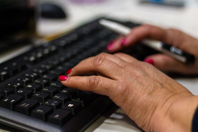 Cropped hands of businesswoman typing on keyboard at desk