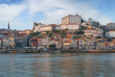 Buildings by river against sky