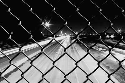 Full frame shot of chainlink fence against sky at night