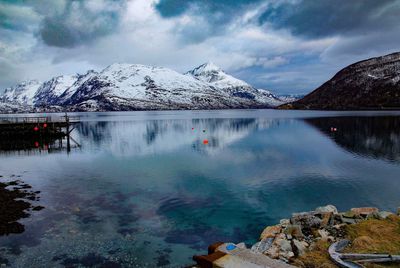 Scenic view of lake by snowcapped mountains against sky