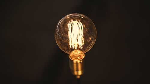 Close-up of illuminated light bulb against black background