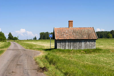 Road amidst field against clear sky