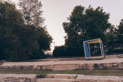 Bench by trees against sky