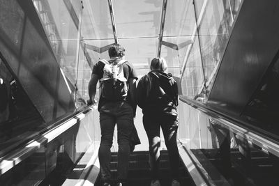 Rear view of couple standing on escalator