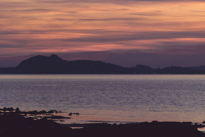 Scenic view of sea against dramatic sky during sunset