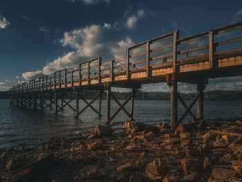 Pier over sea against sky during sunset