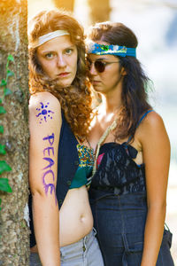 Portrait of lesbian couple standing by tree trunk