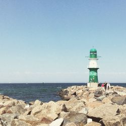 Lighthouse on beach against sky