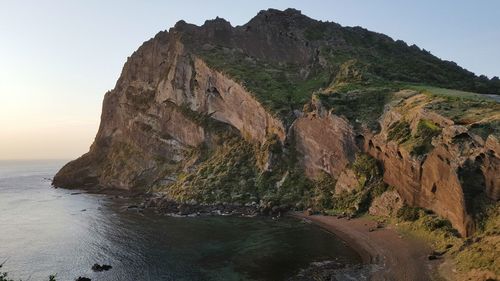 Rock formations by sea against clear sky