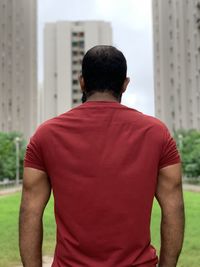 Rear view of man standing against modern buildings in city
