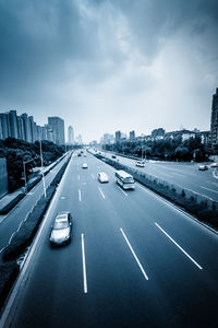 Vehicles on highway against sky in city
