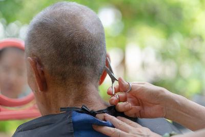 Cropped hand of barber cutting hair outdoors